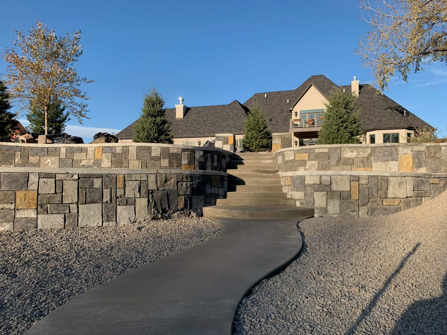 Multi colored decorative retaining wall made of concrete with two tiers. A set of stairs is going up the middle between both walls.