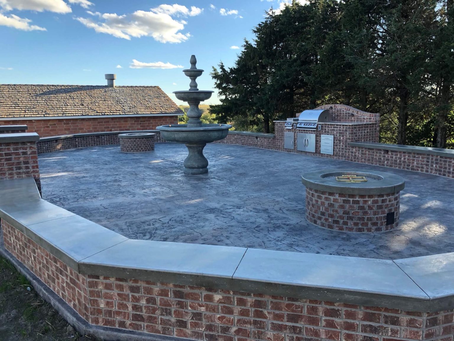 Large outdoor kitchen with red bright. Water fall is in the center with a fire pit on each side of it.